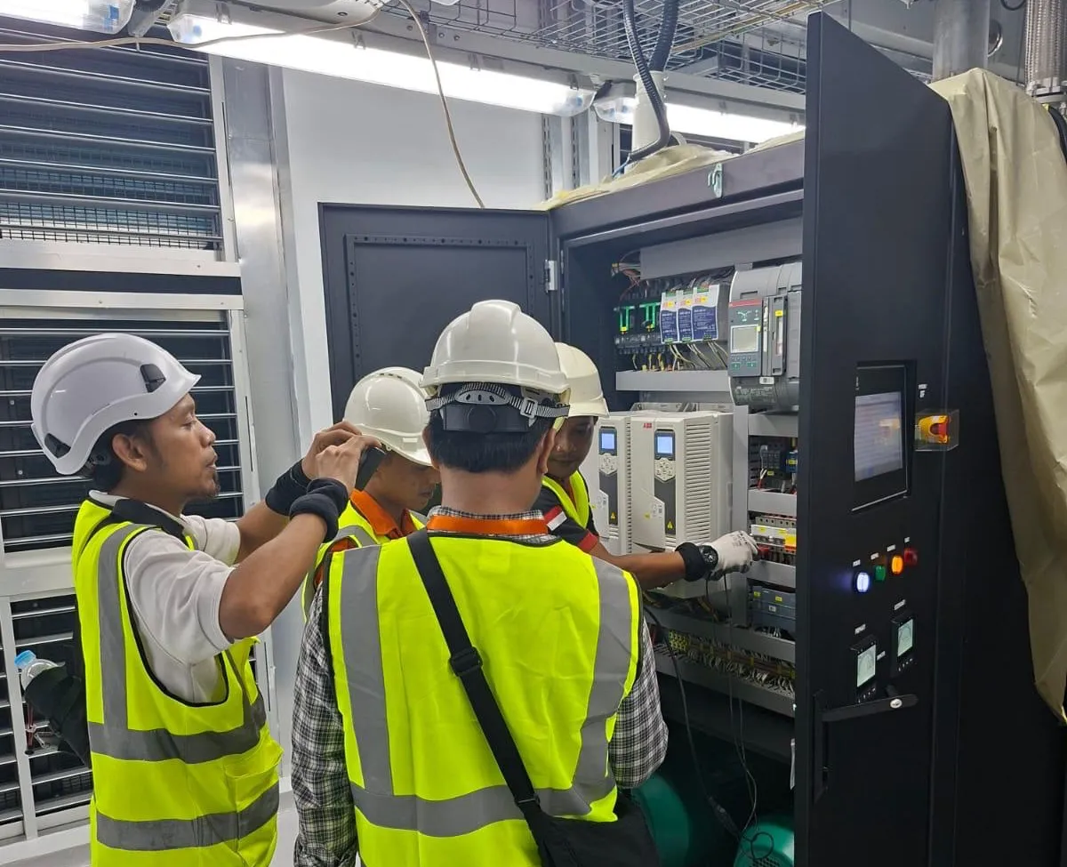 Pariksa engineers and the contractor's team at an open control panel with drives and breakers.