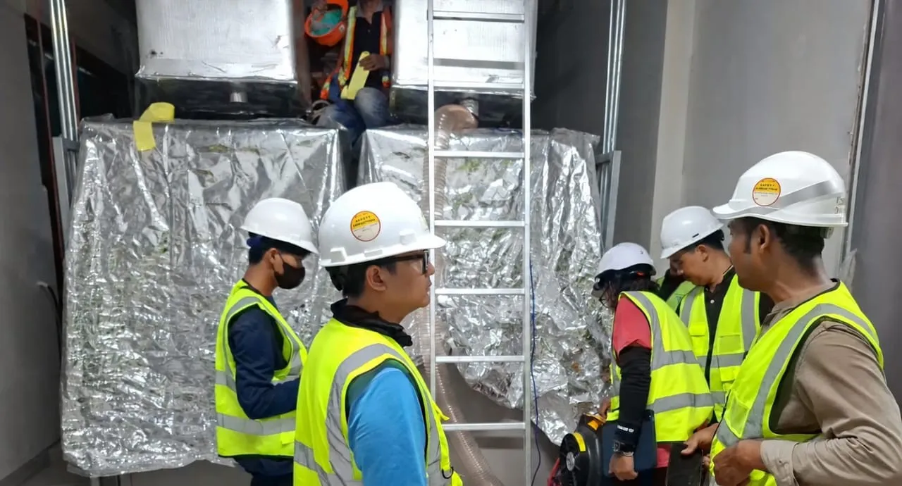 Engineers and the contractor's team at the foil-wrapped battery room ductwork during the evening test shift.