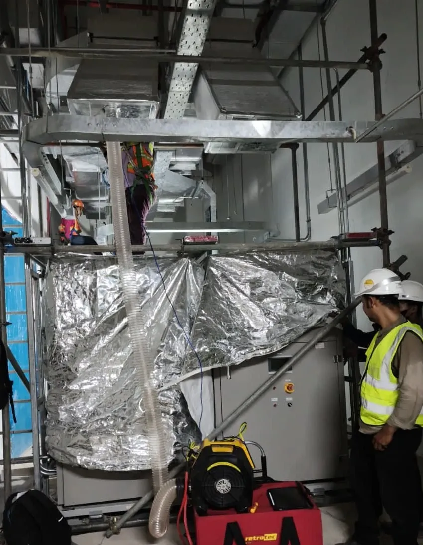 Duct pressure test on a foil-wrapped battery room air handling unit, with a Pariksa engineer at the rig.
